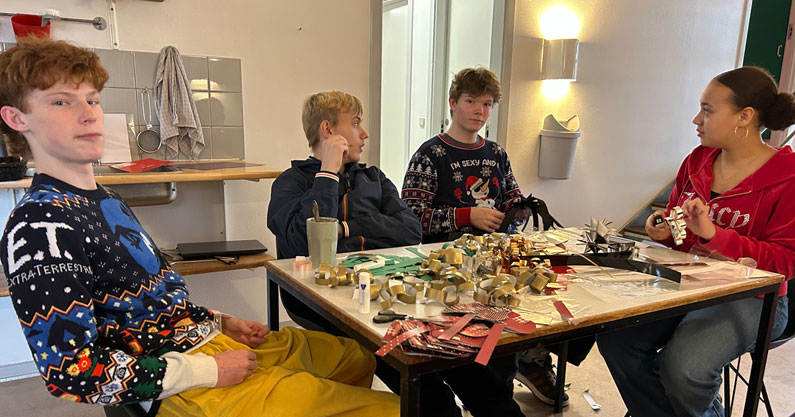 Efterskoleelever klipper julepynt omkring et bord